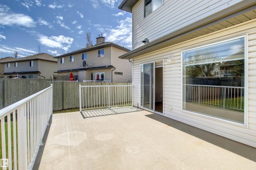 Expansive concrete patio with white metal railing, featuring direct access via a glass sliding door and a large picture window - 8129 7 Avenue, Edmonton, AB - Outdoor With Deck Patio Veranda With Exterior