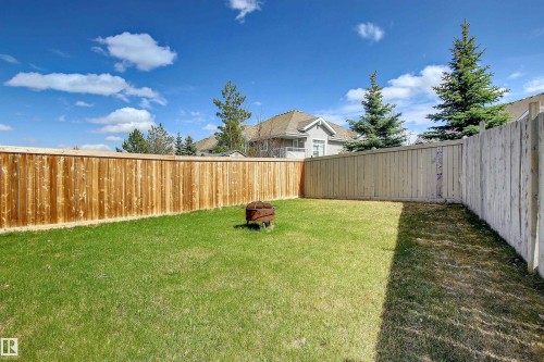 Spacious backyard featuring a lush green lawn, full wood privacy fencing, and mature evergreen trees - 8129 7 Avenue, Edmonton, AB - Outdoor