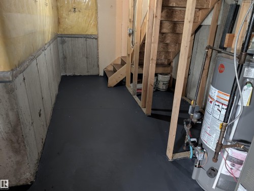 Unfinished basement area featuring concrete walls, a water heater, and exposed wood framing - 8129 7 Avenue, Edmonton, AB - Indoor Photo Showing Other Room