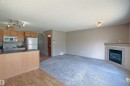 Open-concept living area featuring a kitchen with wood-finish cabinetry, stainless steel appliances, and a breakfast bar - 8129 7 Avenue, Edmonton, AB  - Indoor Photo Showing Kitchen 