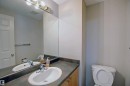 Bathroom vanity with an integrated sink, a dark countertop, and wood-finish cabinetry - 8129 7 Avenue, Edmonton, AB  - Indoor Photo Showing Bathroom 