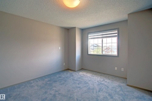 Room featuring neutral-toned walls, blue carpeting, and a grid-pattern window with blinds - 8129 7 Avenue, Edmonton, AB - Indoor Photo Showing Other Room