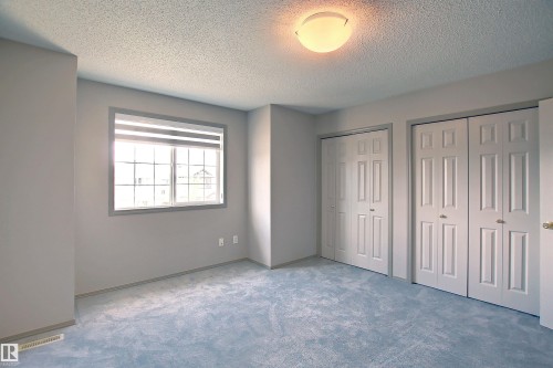 Room featuring a window with integrated blinds, two sets of bi-fold closet doors, wall-to-wall carpeting, and a flush-mount ceiling light fixture - 8129 7 Avenue, Edmonton, AB - Indoor