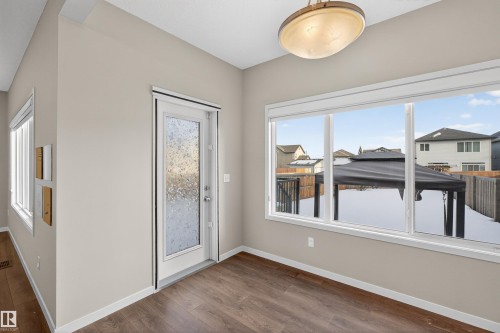 Spacious room featuring wood-finish flooring, a large multi-pane window, and a glass-paneled exterior door - 4723 Alwood Bend Sw, Edmonton, AB - Indoor Photo Showing Other Room