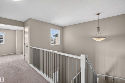 Upper-level landing featuring a staircase with a white railing and dark balusters, neutral wall paint, and recessed lighting - 4723 Alwood Bend Sw, Edmonton, AB - Indoor Photo Showing Other Room