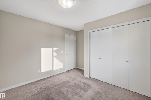 Neutral-toned interior with light tan walls, a textured ceiling, and a flush mount ceiling light fixture - 4723 Alwood Bend Sw, Edmonton, AB - Indoor Photo Showing Other Room