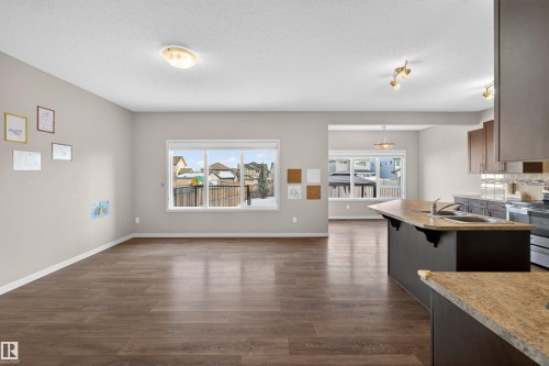 Open-concept living area featuring wood-finish flooring, large windows, and neutral wall tones - 4723 Alwood Bend Sw, Edmonton, AB - Indoor Photo Showing Kitchen