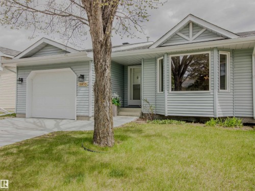 Light blue siding exterior featuring a single-car garage with overhead door, a prominent bay window, and a gabled roofline with decorative trim - 5935 189 Street, Edmonton, AB - Outdoor