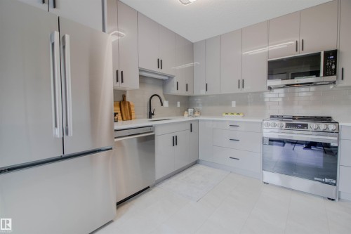 Modern kitchen featuring light gray cabinetry with black hardware, white countertops, and a subway tile backsplash - 5935 189 Street, Edmonton, AB - Indoor Photo Showing Kitchen With Upgraded Kitchen