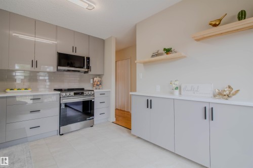 Contemporary kitchen featuring glossy gray cabinetry with black hardware - 5935 189 Street, Edmonton, AB - Indoor Photo Showing Kitchen With Upgraded Kitchen