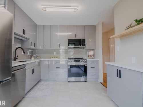 Contemporary kitchen featuring light gray cabinetry with black hardware, white countertops, and a subway tile backsplash - 5935 189 Street, Edmonton, AB - Indoor Photo Showing Kitchen With Upgraded Kitchen