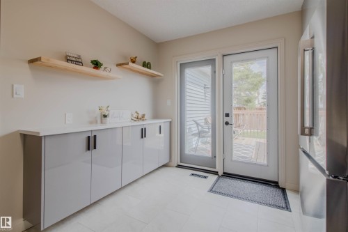 Contemporary cabinetry with a light countertop and wood floating shelves, complemented by light tile flooring - 5935 189 Street, Edmonton, AB - Indoor Photo Showing Other Room