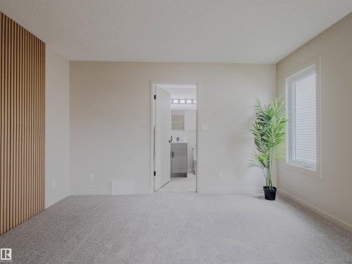 Spacious room featuring light gray carpeting, a window with horizontal blinds, and a distinctive wood slat accent wall - 5935 189 Street, Edmonton, AB - Indoor Photo Showing Other Room