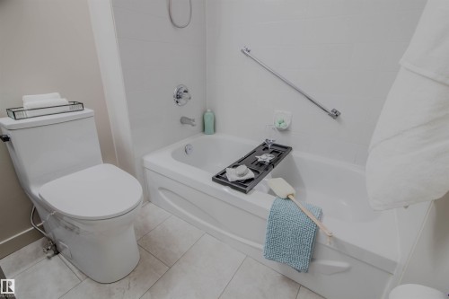 Bathroom featuring a deep soaking tub with chrome fixtures, a wall-mounted grab bar, and a two-piece toilet - 5935 189 Street, Edmonton, AB - Indoor Photo Showing Bathroom