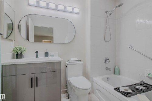 Bathroom featuring a white bathtub, white tiled shower surround, and a modern vanity with a rectangular sink - 5935 189 Street, Edmonton, AB - Indoor Photo Showing Bathroom