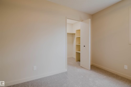 Bedroom featuring neutral wall paint, light gray carpeting, and a closet with shelving and a hanging rod - 5935 189 Street, Edmonton, AB - Indoor Photo Showing Other Room