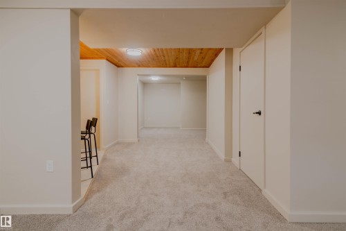 Spacious interior featuring light gray carpeting and a wood-paneled ceiling - 5935 189 Street, Edmonton, AB - Indoor Photo Showing Other Room