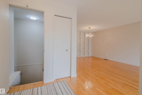 Open interior featuring wood-finish flooring, light-toned walls, and a modern ceiling fixture - 5935 189 Street, Edmonton, AB - Indoor Photo Showing Other Room