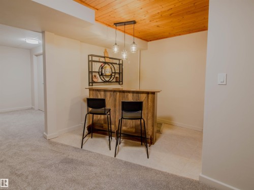 Custom-built bar featuring wood paneling, a wood countertop, and a decorative metal shelving unit - 5935 189 Street, Edmonton, AB - Indoor Photo Showing Other Room