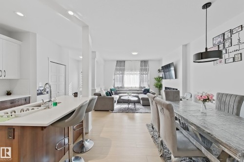 Kitchen island featuring a single-basin sink with a gooseneck faucet, light-toned countertop, and wood-finish cabinetry - 1231 Watt Drive, Edmonton, AB - Indoor