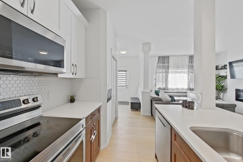 Contemporary kitchen featuring white cabinetry, a hexagon tile backsplash, stainless steel appliances, and light-toned wood-finish flooring - 1231 Watt Drive, Edmonton, AB - Indoor Photo Showing Kitchen With Stainless Steel Kitchen With Upgraded Kitchen