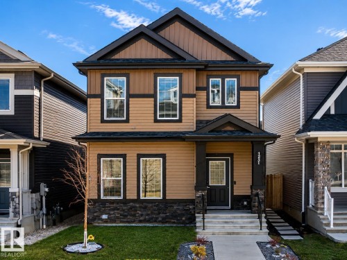 Two-story exterior featuring tan siding, dark trim, and a stone accent foundation - 1231 Watt Drive, Edmonton, AB - Outdoor With Facade