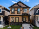 Two-story exterior featuring tan siding, dark trim, and a stone accent foundation - 1231 Watt Drive, Edmonton, AB  - Outdoor With Facade 