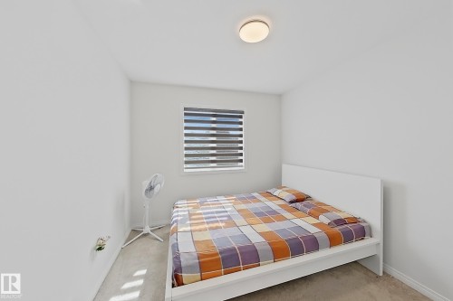 Bright room with a flush-mount ceiling light fixture, neutral carpeting, and a window featuring horizontal blinds - 1231 Watt Drive, Edmonton, AB - Indoor Photo Showing Bedroom