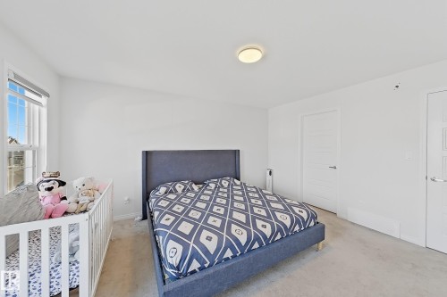 Bright bedroom featuring a double-hung window, light carpeting, and a flush-mount ceiling light - 1231 Watt Drive, Edmonton, AB - Indoor Photo Showing Bedroom