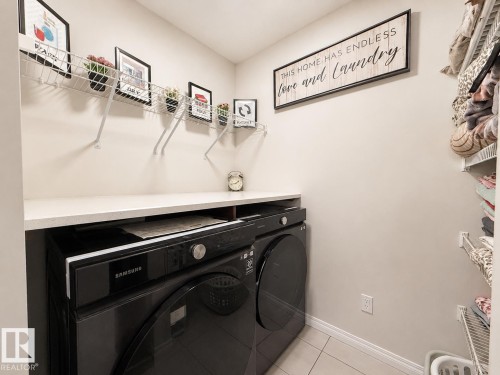 Dedicated laundry area featuring a built-in countertop, integrated washer and dryer, tiled flooring, and wall-mounted wire shelving - 1231 Watt Drive, Edmonton, AB - Indoor Photo Showing Laundry Room