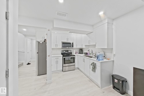 Contemporary kitchen featuring white cabinetry, stainless steel appliances, light-toned flooring, recessed lighting, and a white countertop - 1231 Watt Drive, Edmonton, AB - Indoor Photo Showing Kitchen With Double Sink