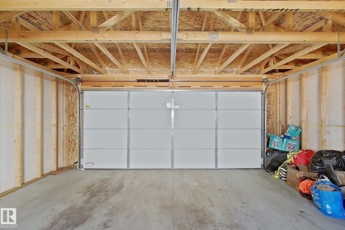 Garage space featuring exposed wood framing, a concrete floor, and a segmented overhead door - 1231 Watt Drive, Edmonton, AB - Indoor Photo Showing Garage
