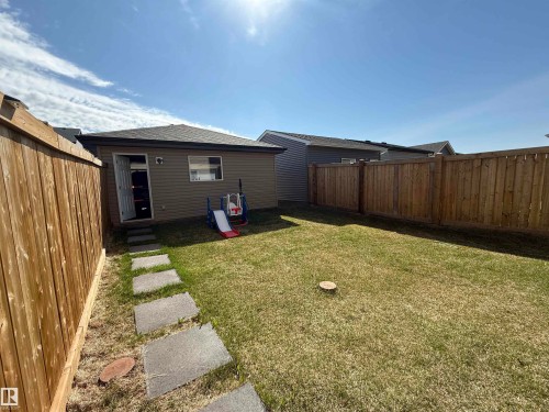 Fenced backyard featuring a manicured lawn, a concrete paver pathway, and wood privacy fencing - 1231 Watt Drive, Edmonton, AB - Outdoor
