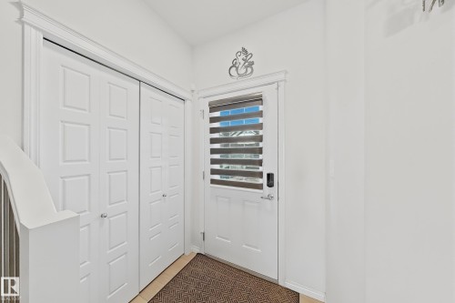 Entry foyer featuring a paneled door with integrated blind, adjacent bi-fold closet doors, a neutral tone floor mat, and white painted walls - 1231 Watt Drive, Edmonton, AB - Indoor Photo Showing Other Room