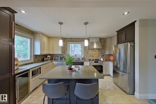 Modern kitchen featuring a central island with integrated seating, recessed lighting, and pendant fixtures - 10 Brunswick Crescent, St. Albert, AB - Indoor