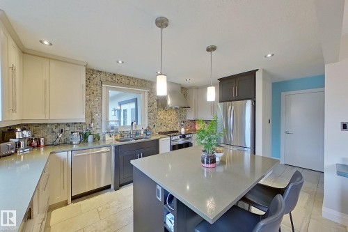 Contemporary kitchen featuring a central island with seating, stainless steel appliances, upper and lower cabinetry, recessed lighting, and a mosaic tile backsplash - 10 Brunswick Crescent, St. Albert, AB - Indoor Photo Showing Kitchen With Upgraded Kitchen