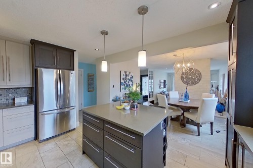 Kitchen featuring a large central island with a light-toned countertop, stainless steel refrigerator, tile flooring, and integrated display shelving - 10 Brunswick Crescent, St. Albert, AB - Indoor Photo Showing Other Room