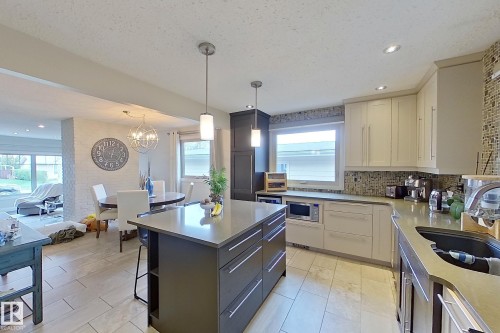 Modern kitchen featuring a large center island with integrated storage, stainless steel appliances, mosaic tile backsplash, recessed lighting, and tile flooring - 10 Brunswick Crescent, St. Albert, AB - Indoor Photo Showing Kitchen With Upgraded Kitchen