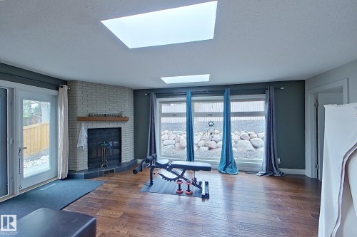 Spacious interior featuring wood-finish flooring, two skylights, and a corner brick fireplace with a wood mantle - 10 Brunswick Crescent, St. Albert, AB - Indoor With Fireplace