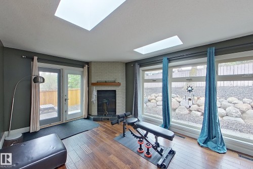 Interior space featuring wood-finish flooring, two skylights, and a light brick fireplace with a wood mantle - 10 Brunswick Crescent, St. Albert, AB - Indoor
