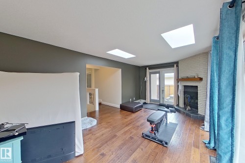 Living area featuring wood-finish flooring, two skylights, and a brick fireplace with a wood mantle - 10 Brunswick Crescent, St. Albert, AB - Indoor