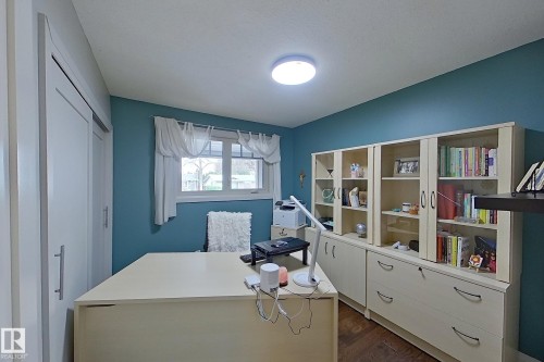 Room featuring wood-finish flooring, a window with natural light, and a built-in shelving unit with lower drawer storage - 10 Brunswick Crescent, St. Albert, AB - Indoor Photo Showing Office