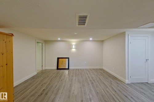 Spacious room featuring wood-finish flooring, recessed lighting, a modern wall sconce, and a clean white door - 10 Brunswick Crescent, St. Albert, AB - Indoor Photo Showing Other Room