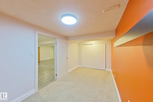 Carpeted interior space featuring a ceiling-mounted light fixture, white trim, and a built-in closet with sliding doors - 10 Brunswick Crescent, St. Albert, AB - Indoor Photo Showing Other Room