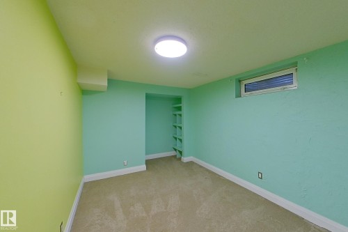 Carpeted room featuring a ceiling-mounted light fixture, a rectangular window with blinds, and built-in shelving - 10 Brunswick Crescent, St. Albert, AB - Indoor Photo Showing Other Room
