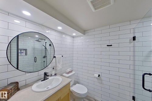 Bathroom featuring white subway tile walls, a frameless glass shower enclosure, a vanity with an integrated sink, a circular mirror with a black frame, and recessed lighting - 10 Brunswick Crescent, St. Albert, AB - Indoor Photo Showing Bathroom