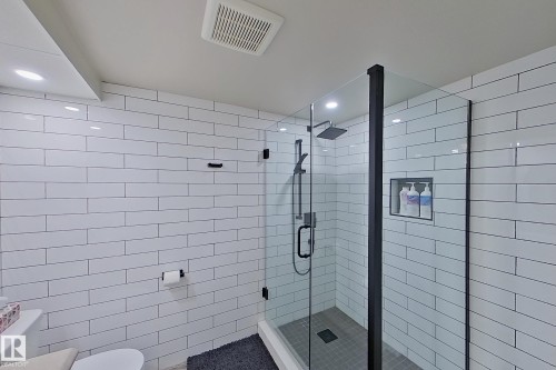 Contemporary bathroom featuring white subway tile walls, a glass-enclosed shower with matte black fixtures, a built-in shower niche, and recessed ceiling lighting - 10 Brunswick Crescent, St. Albert, AB - Indoor Photo Showing Bathroom