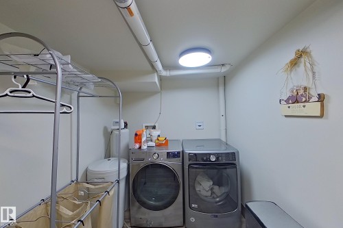 Dedicated laundry area featuring a front-loading washer and dryer, ceiling-mounted light fixture, and visible utility piping - 10 Brunswick Crescent, St. Albert, AB - Indoor Photo Showing Laundry Room