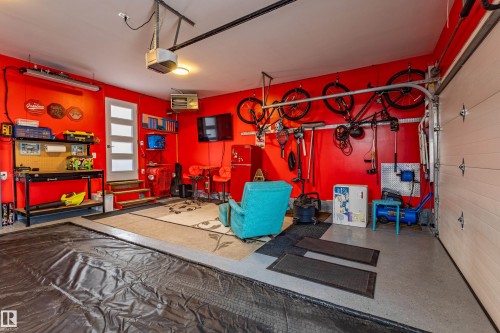 Finished garage with epoxy flooring, red-painted walls, a modern entry door, and built-in shelving - 10 Brunswick Crescent, St. Albert, AB - Indoor