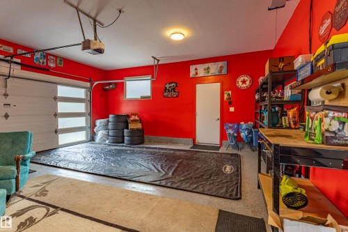 Spacious garage featuring a modern overhead door with frosted glass panels, durable epoxy-coated flooring, and a workshop area with built-in shelving - 10 Brunswick Crescent, St. Albert, AB - Indoor Photo Showing Garage